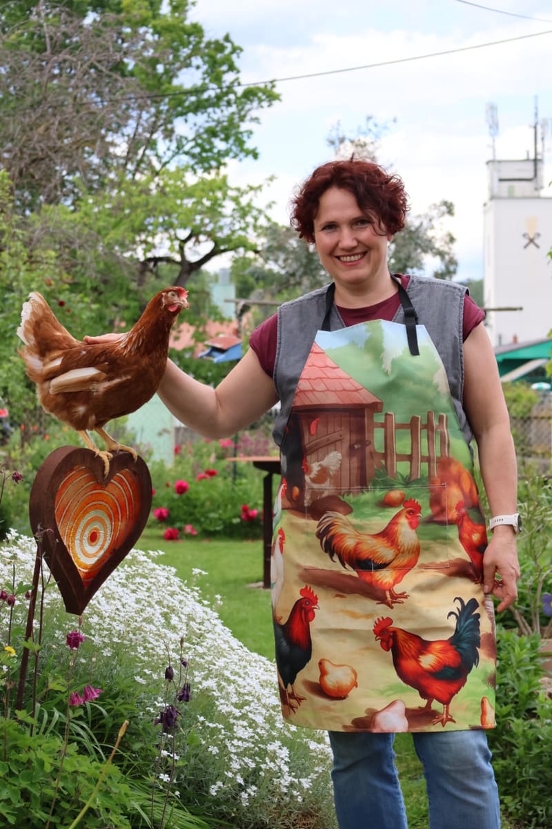 Veronika Schweiger-Mauschitz mit einer Henne auf der Hand im Garten